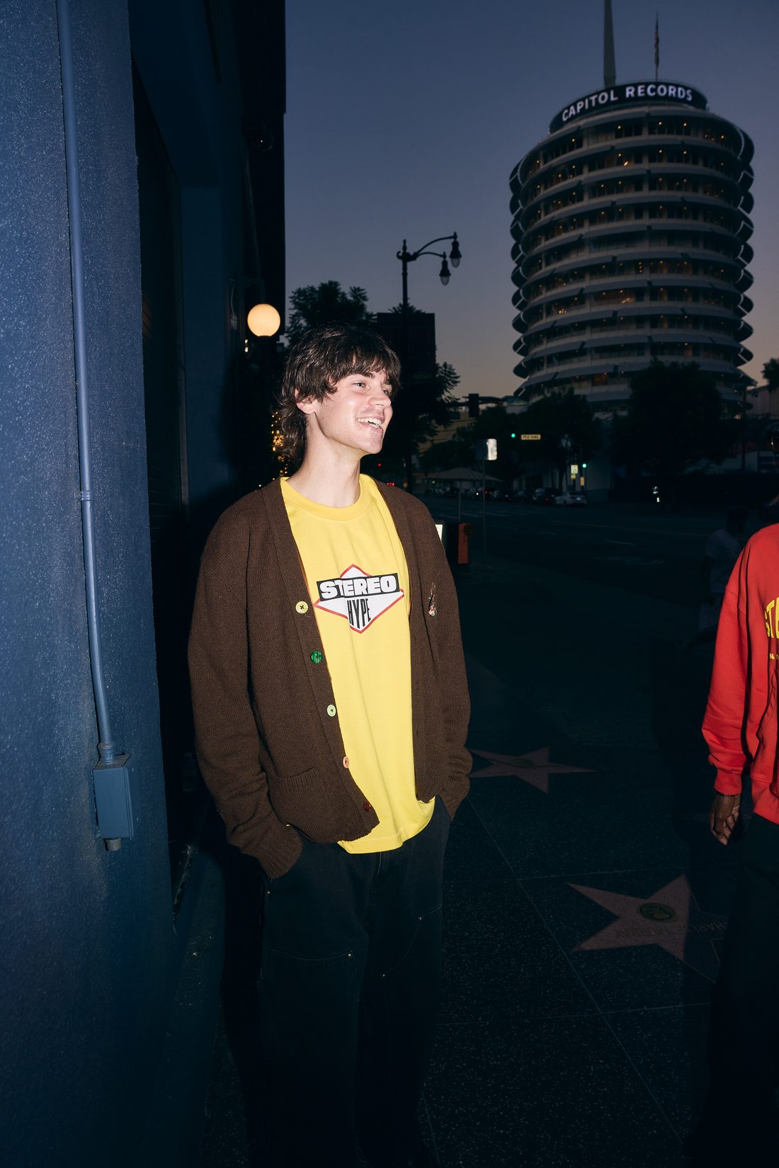 Yellow STEREO HYPE diamond tee under a brown cardigan, Hollywood Walk of Fame at sunset