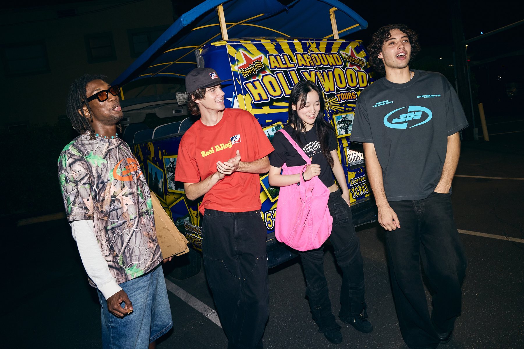 Four models in front of a Hollywood tour bus, laughing